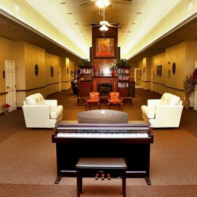 Long common area with black piano and two white couches