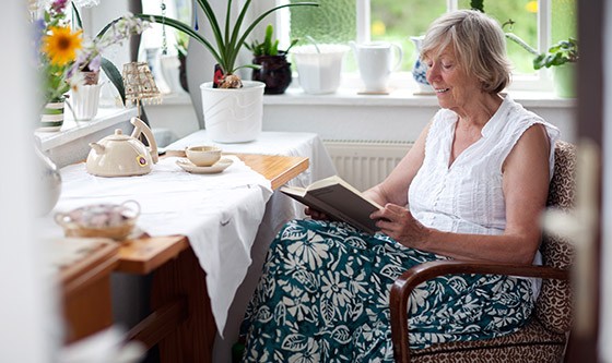 Older woman smiling while reading a book inside