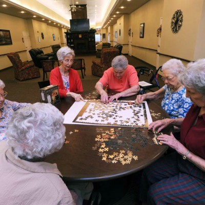 Group of elderly women working on a large jigsaw puzzle together